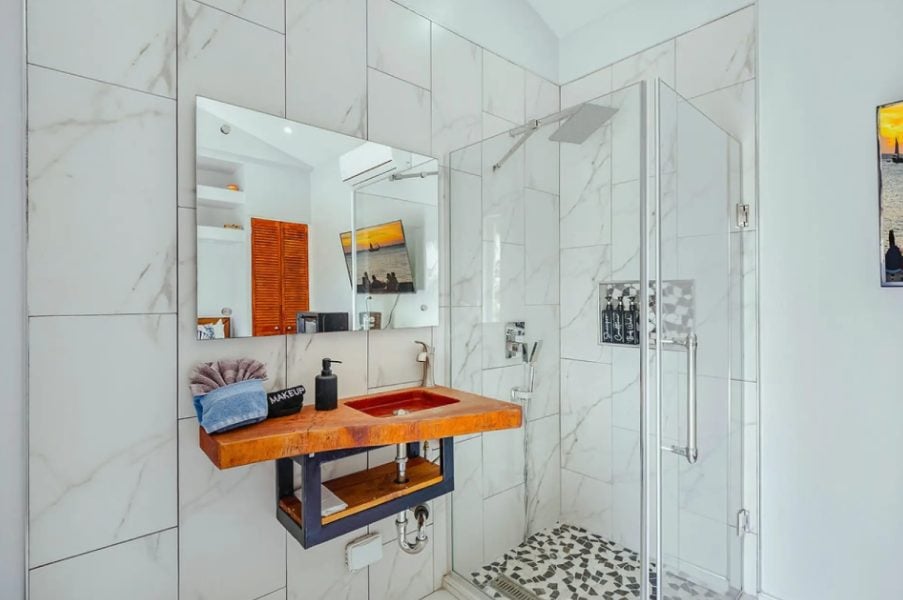 Marble bathroom with orange wooden vanity and walk-in shower