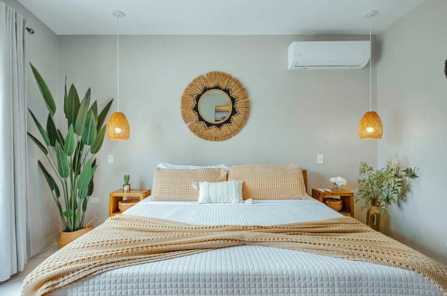 Bedroom with white bedding, rattan details and round mirror