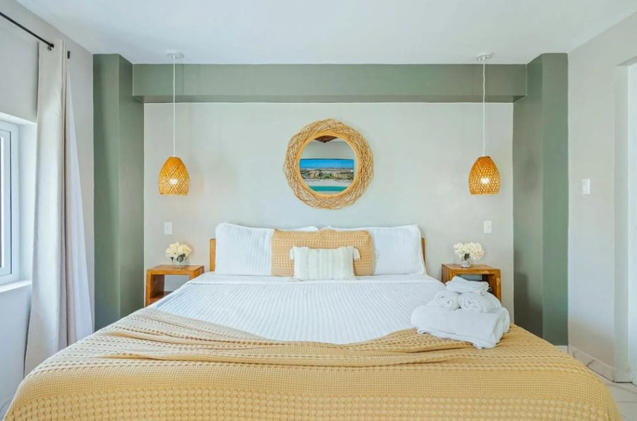 Bedroom with sage green wall and round mirror
