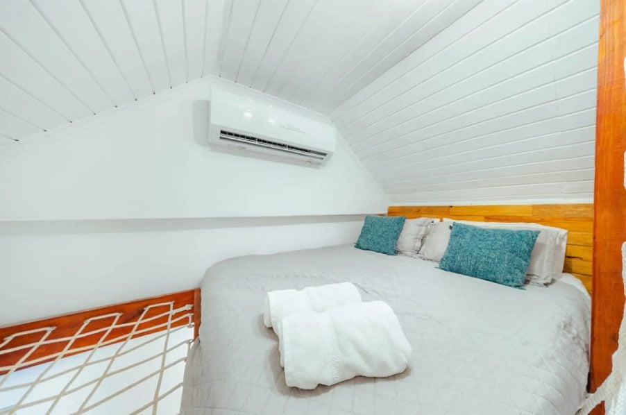Loft bed with teal cushions and wall-mounted air conditioner