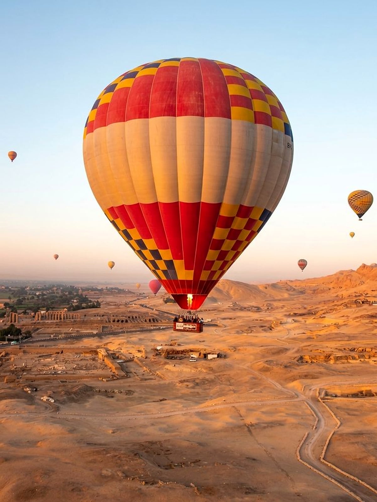 A hot air balloon floating over desert terrain at sunrise